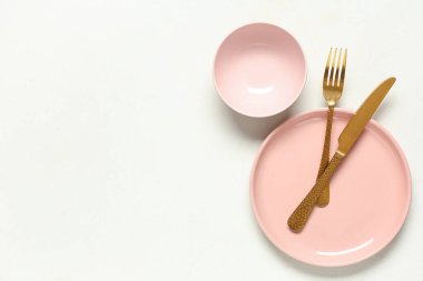 Beyaz arka planda altın çatal bıçak seti olan güzel bir masa.