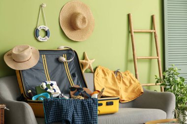 Kanepede erkek mayosu ve plaj aksesuarlarıyla valizi aç, yakın plan.