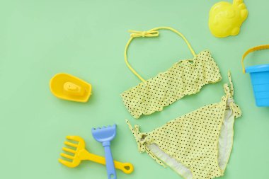 Yeşil arka planda plaj oyuncakları olan çocuk mayosu.