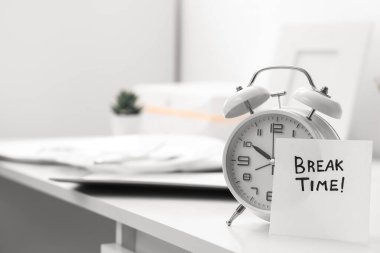 Ofisteki masasında kısa mesaj zamanı ve çalar saati olan kağıt, yakın plan.