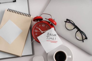 Yazılı kağıt. Kırık saat, çalar saat, kahve fincanı ve laptop beyaz masada, üst görünümde.