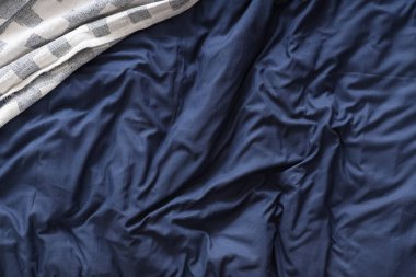 Yatağın üstünde lacivert battaniye, üst manzara.