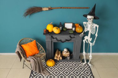 Cadılar Bayramı için dekore edilmiş oturma odasının içinde şömine, koltuk ve insan iskeleti var.