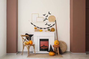 Cadılar Bayramı için dekore edilmiş oturma odasının içinde şömine, sandalye ve balkabakları var.