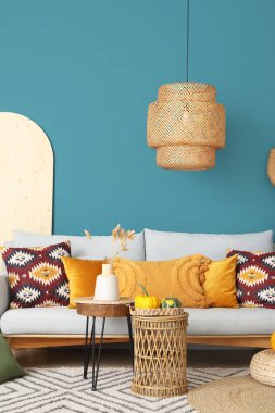 Mavi duvarın yanında rahat kanepe, masa ve balkabağı olan bir oturma odası.