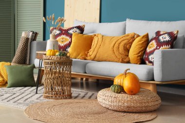 Mavi duvarın yanında kanepe, masa, puf ve balkabağı olan bir oturma odası.