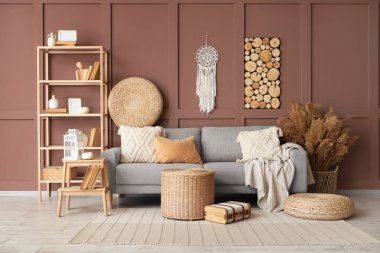 Rahat bir kanepe, hasır masa, merdiven ve raflar oturma odasının içinde.