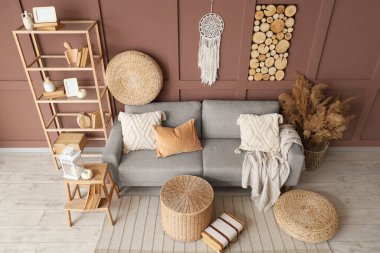 Rahat bir kanepe, hasır masa ve vazo. Oturma odasının içinde otlar var.