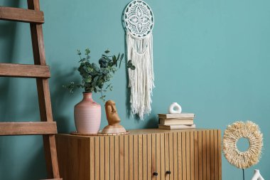 Yapay okaliptüs dallı vazo, heykel ve odada klozetle ilgili kitaplar.