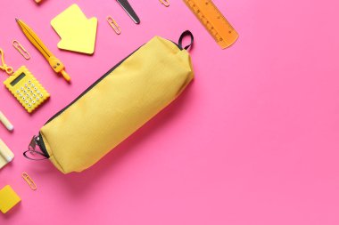 Pembe arka planda farklı kırtasiye malzemesi olan sarı kalem kutusu. Üst görünüm