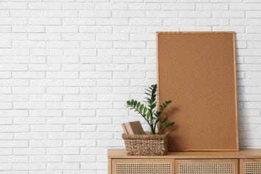 Çekmeceler, ev bitkisi ve çerçeve beyaz tuğla duvarın yanında.
