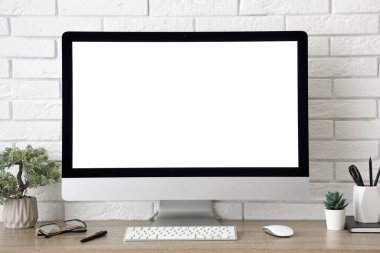 Işık ofisindeki beyaz tuğla duvarın yanında bilgisayar ve kırtasiye malzemesi olan şık bir iş yeri