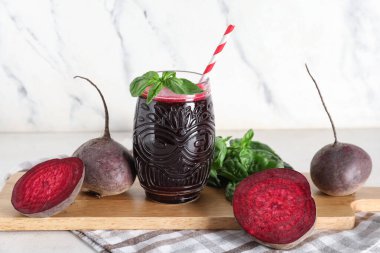 Beyaz arka planda fesleğenli ve sebzeli taze pancar suyu.