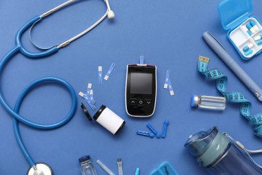 Mavi arka planda neşter, şerit, insülin ve steteskoplu glukometre. Diyabet kavramı