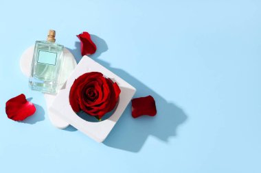 Dekoratif podyumlar, bir şişe parfüm ve mavi arka planda güzel kırmızı bir gül. Sevgililer Günü kutlaması