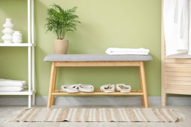 Rafları, terlikleri ve gri bankları olan şık bir banyo.