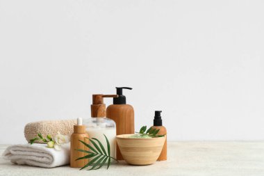 Hafif arkaplanda kozmetik ürünler, banyo süngeri, havlu ve bitki yaprakları