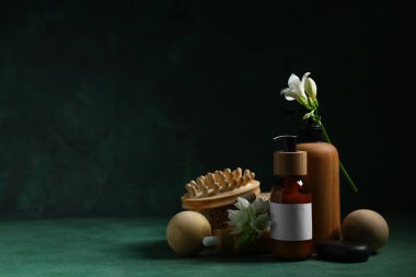 Kaplıca aksesuarları, kozmetik ürünleri ve koyu renk arka planda güzel çiçekler içeren kompozisyon