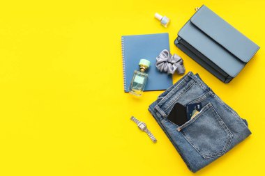 Sarı arka planda şık kadın aksesuarları, giysileri, not defteri ve cep telefonu kompozisyonu