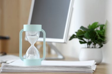 Ofisteki kağıtların üzerindeki kum saati, yakın çekim.