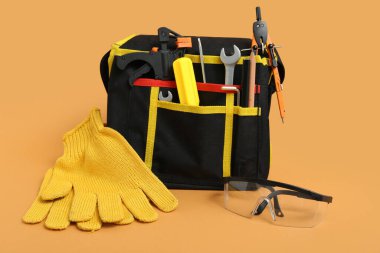 Marangoz aletleri, eldivenler ve bej arka planda koruyucu gözlüklü çanta.