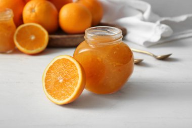 Beyaz ahşap arka planda lezzetli turuncu reçel kavanozu