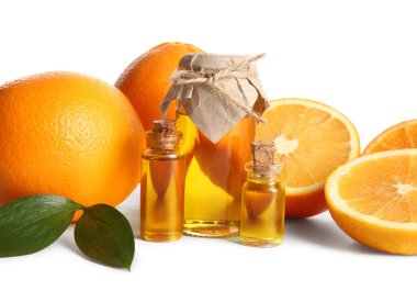 Portakal yağı şişeleri ve beyaz arka planda taze meyveler.