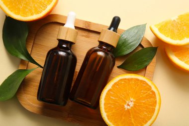 Portakal yağı şişeleri ve bej arka planda taze meyveler.