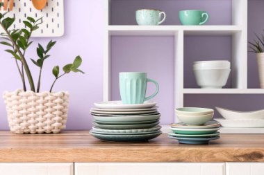 Mutfaktaki ahşap tezgahta temiz tabaklar, kaseler ve bardaklar, yakın plan.