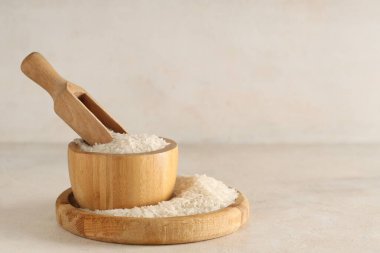 Ahşap tepsi ve arka planda kepçeyle çiğ pirinç.