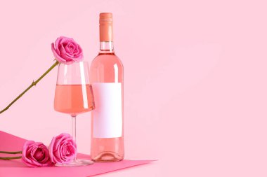 Bir bardak pembe şarap ve arka planda güzel güller.