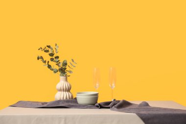 Okaliptüslü vazo ve sarı arka planda masa örtüsü.