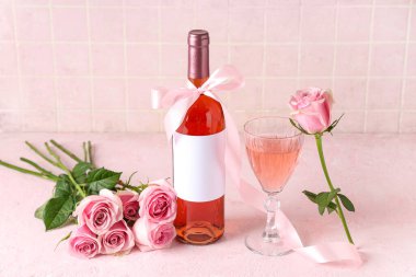 Bir şişe pembe şarap ve güzel güller masasında