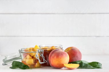 Kavanozlar dolusu lezzetli şeftali reçeli ve açık ahşap masada taze meyveler.