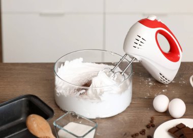 Mutfaktaki masada çırpılmış yumurta albümleriyle karıştırıcı, yakın plan.