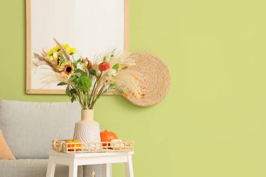 Sonbahar çiçekli vazo ve oturma odasındaki taburede kabak.