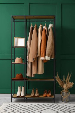 Salondaki yeşil duvarın yanında şapka, çerçeve ve ayakkabı askısı.