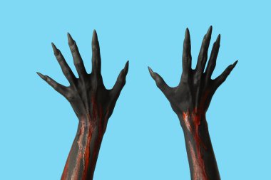 Mavi arka planda pençeleri olan siyah cadı elleri. Cadılar Bayramı