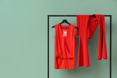 Kırmızı elbiseli raflar ve yeşil arka planda indirim etiketleri