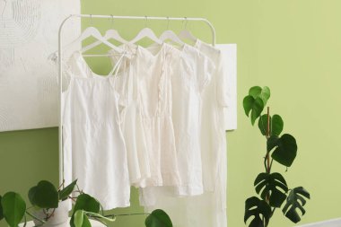 Giyim mağazasında yeşil duvarın yanında beyaz elbiseli raflar