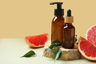 Kozmetik ürünleri, taş ve greyfurt parçaları bej duvarın yanındaki yeşil masada, yakın plan.