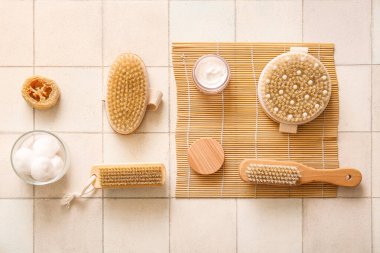 Bambu hasırlı kompozisyon, kozmetik ürünler kavanozu ve bej kaplamalı farklı masaj vücut fırçaları.