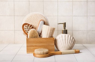 Kozmetik ürünler şişesi, ahşap kutu ve bej kaplamalı farklı masaj vücut fırçaları, yakın plan.