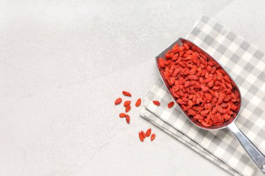 Beyaz grunge arka planda kurutulmuş kurt üzümlü metal kepçesi, yakın plan.