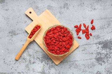 Gri grunge arka planda kurutulmuş goji üzümleri ile kase ve kepçe