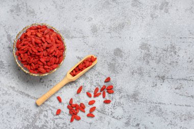 Gri grunge arka planda kurutulmuş goji üzümleri ile kase ve kepçe