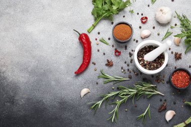 Bitkilerle, havan toplarıyla ve gri grunge arka planda baharatlı kaselerle kompozisyon