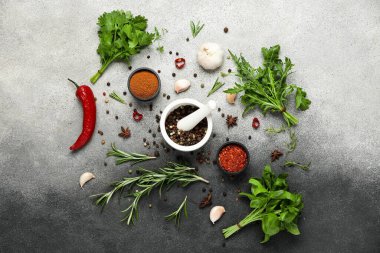 Bitkilerle, havan toplarıyla ve gri grunge arka planda baharatlı kaselerle kompozisyon