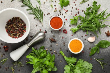 Bitkiler, havan, tokmak ve gri grunge arka planda baharatlar içeren kaselerle kompozisyon, yakın plan