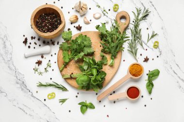 Ahşap kesim tahtasıyla kompozisyon, mermer arka planda bitkiler ve baharatlar